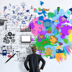 young man facing large wall looking up at brainstorm and artistic graphics